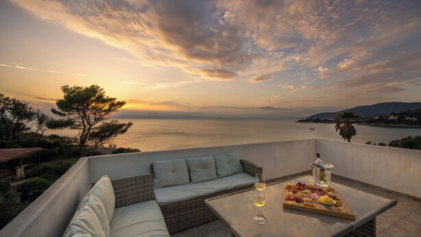 A terrace with a wicker sofa, a glass table with a bottle and a fruit platter, and a view of the sea at sunset. - Amazing sunset from the pool, 30 meters from the sea! (Torre Delle Stelle)