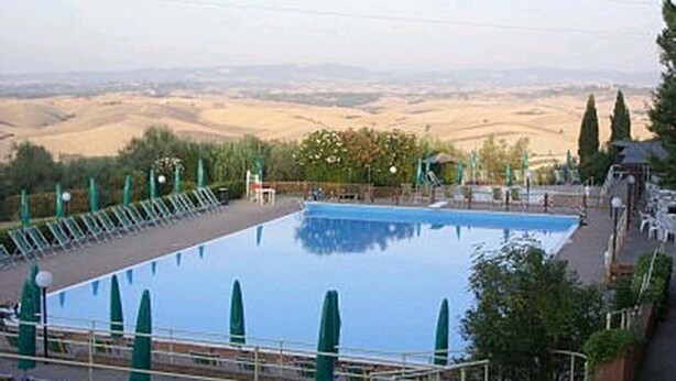 A rectangular swimming pool with a clear view of the surrounding landscape, including rolling hills and trees.