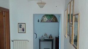 A hallway with a tiled floor, a radiator, a wooden cabinet, and a table with decorative items.