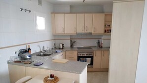 A compact kitchen with a sink, stove, and cabinets.