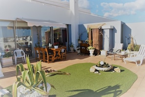 Enjoy al fresco dining and relaxation in this serene outdoor space with a dining table, lounge chairs, and a charming garden.