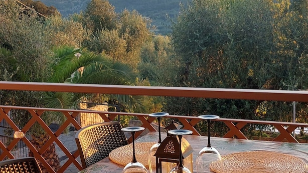 Un espace extérieur aménagé pour prendre les repas, offrant une vue sur les collines et les arbres.