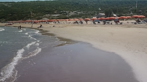 Une plage avec des parasols orange et des gens qui se détendent.