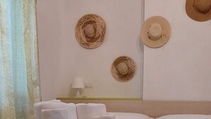 Une chambre d’hôtel avec un lit, un porte-chapeau fixé au mur et un porte-serviettes en macramé avec des serviettes pliées.