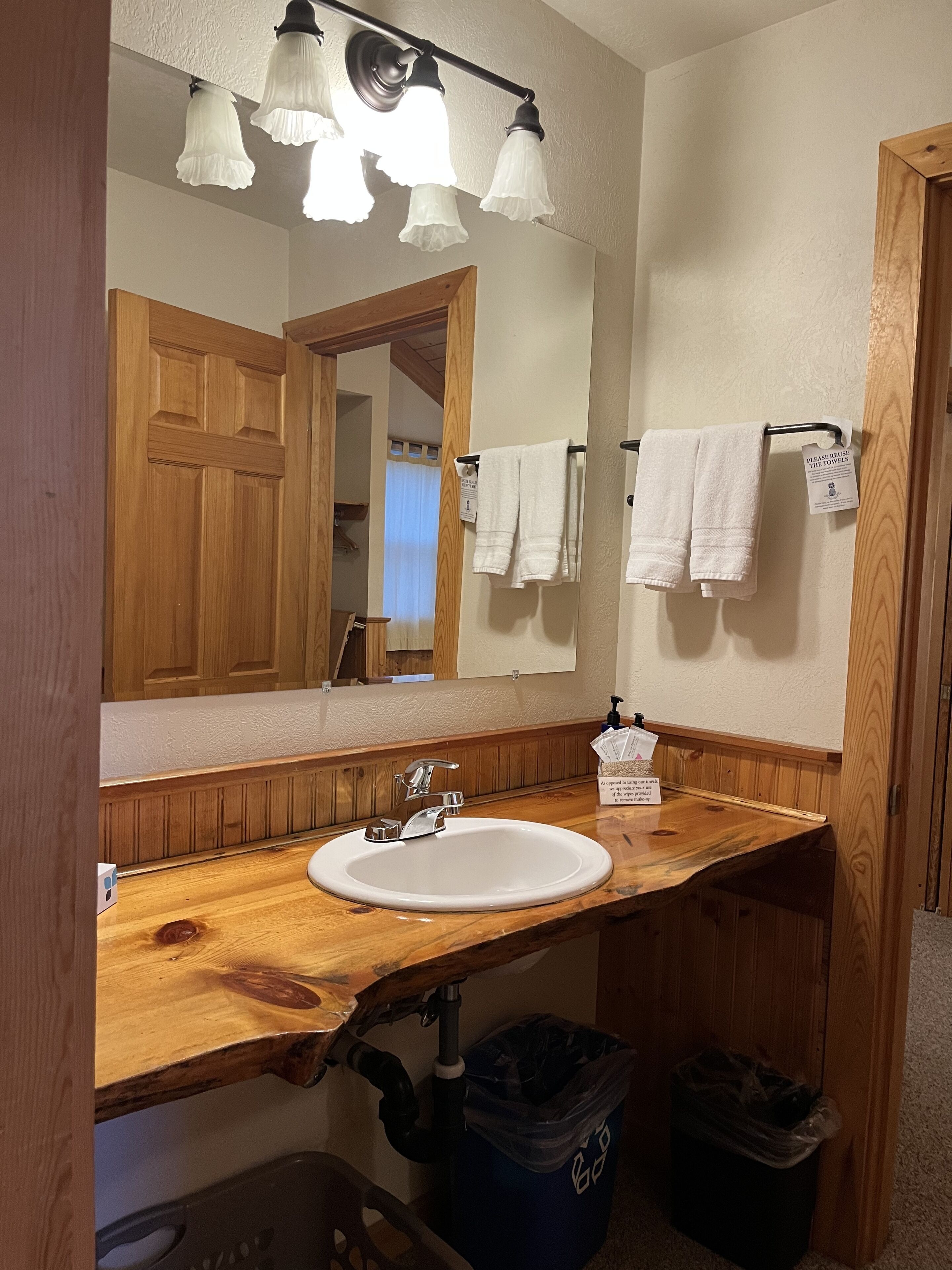 A bathroom with a wooden vanity, a white sink, a mirror, and a towel rack.