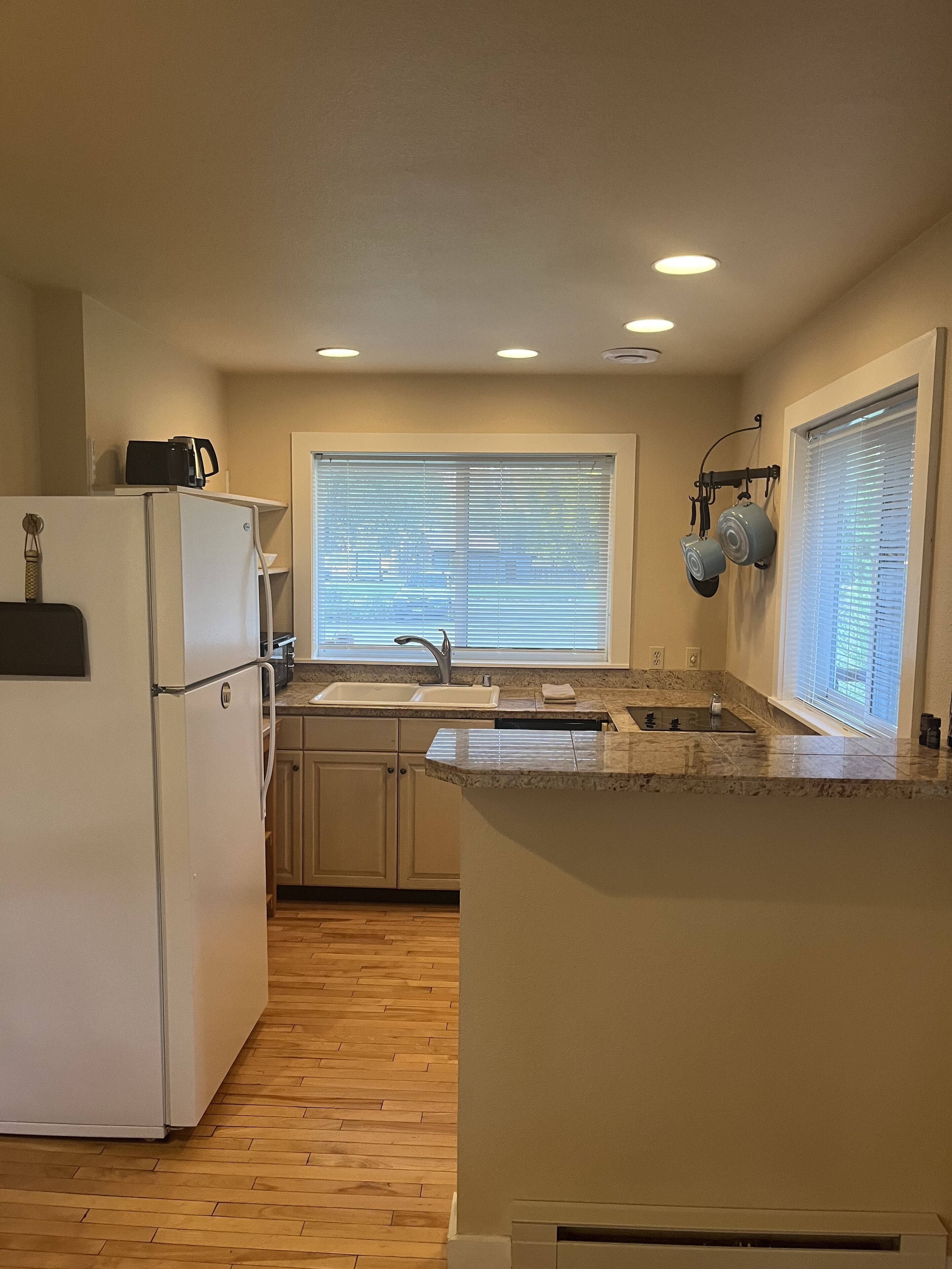 Una cocina compacta con refrigerador, lavamanos y ventana con persianas.