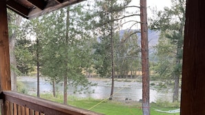 Una terraza de madera con barandilla da vista a un río y árboles.
