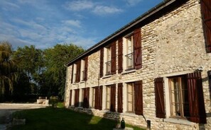 Un edificio de piedra con numerosas ventanas y un césped bien cuidado.