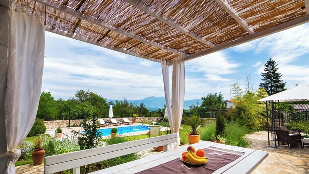 Un espace extérieur abrité comprenant une piscine, des bancs et une table avec des fruits.