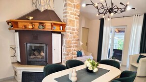 Un coin repas agrémenté d’une cheminée, d’un mur en pierre et d’un lustre.