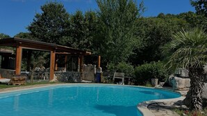 A swimming pool with a wooden deck, surrounded by greenery and a stone pathway. - Villa Aresini - Events & Exclusive Residence (Montemiletto)