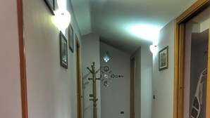A hallway with wooden flooring, framed pictures on the walls, and a coat rack. - Villa Aresini - Events & Exclusive Residence (Montemiletto)