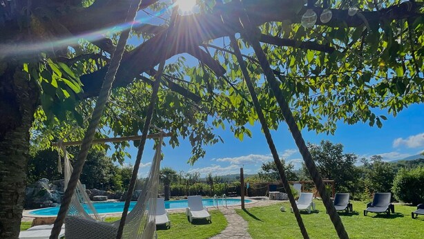 A hammock under a tree, a pool, and lounge chairs in a sunny outdoor setting. - Villa Aresini - Events & Exclusive Residence (Montemiletto)