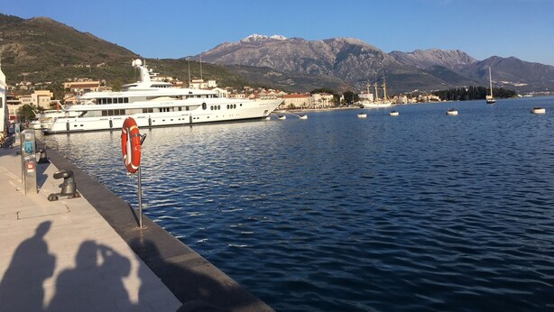 A waterfront marina with boats, a lifebuoy, and a mountainous backdrop.