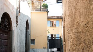 Une ruelle étroite, avec des chemins pavés, des murs de pierre et un petit espace aménagé en jardin.