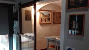 Une pièce avec un plancher en bois, une table entourée de chaises, un tableau accroché au mur et un panneau indiquant l’utilisation d’un gel désinfectant.