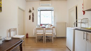 Een keuken met een eettafel, stoelen, een radiator en een raam.