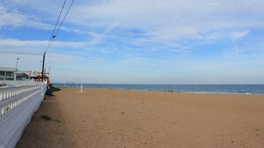 En strand med et volleyballnet, et hvidt hegn og en bygning pyntet med flag.