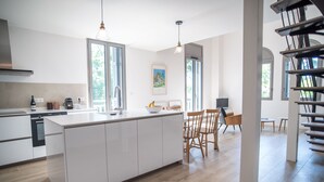 Et moderne køkken med en central ø, træstole og et spisebord.