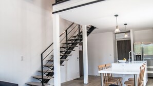 Et moderne interiør med trappe, spiseplads og køkken.