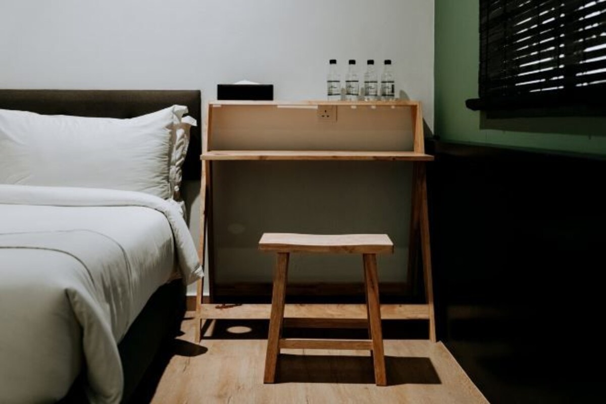 A bedroom with a bed, a wooden nightstand, and a small table.