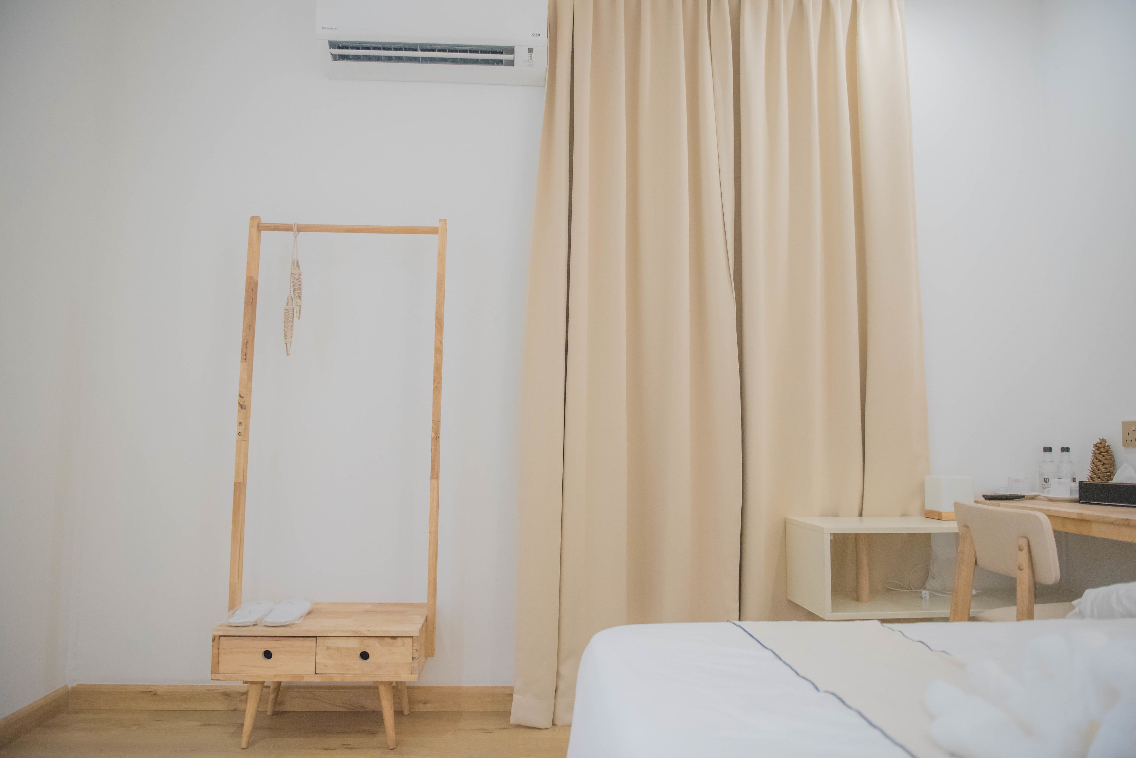 Um quarto minimalista com um guarda-roupa de madeira, uma escrivaninha com cadeira e uma cama.