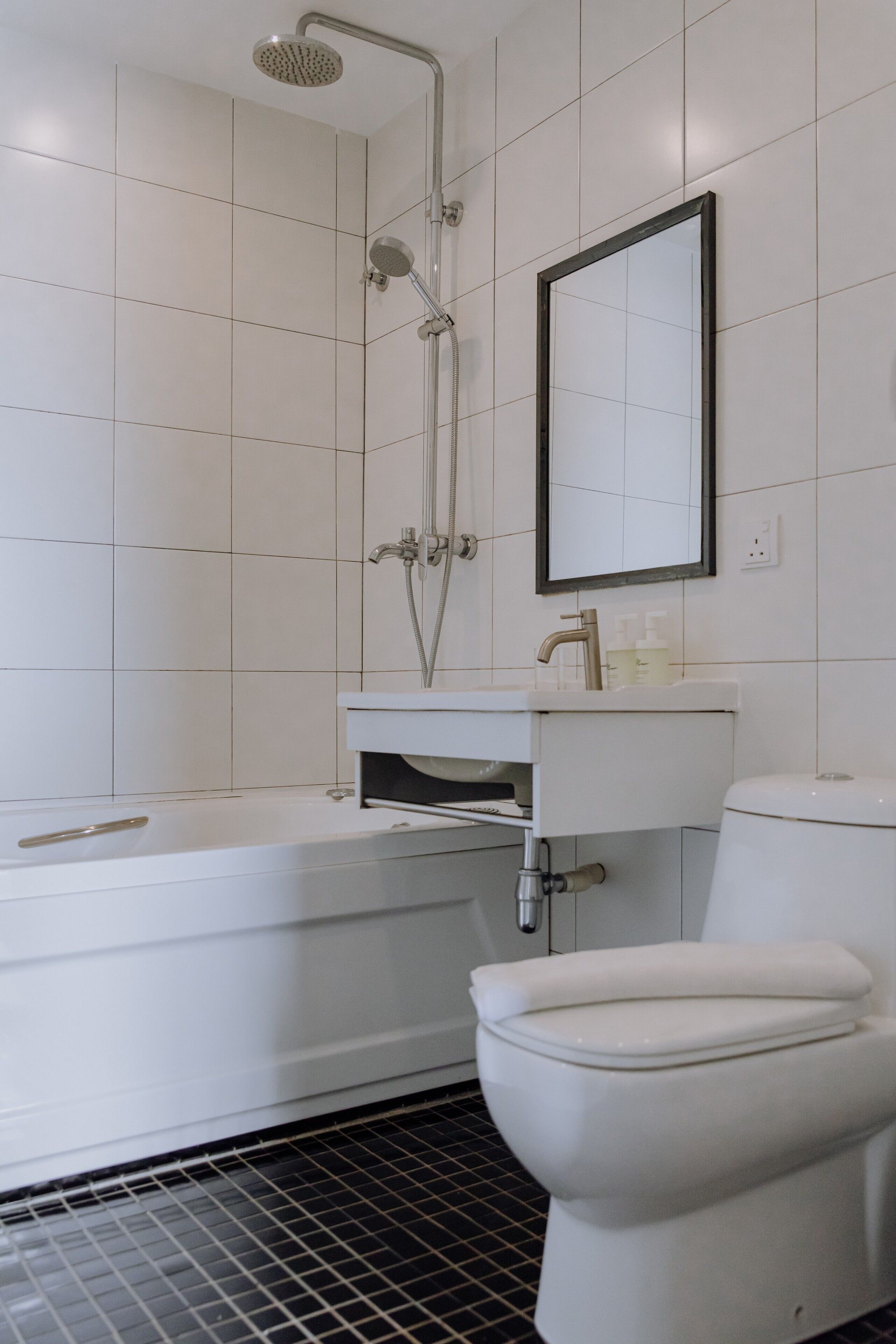 A bathroom with a bathtub, toilet, sink, and a showerhead.