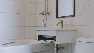 A bathroom with a bathtub, toilet, sink, and a showerhead.