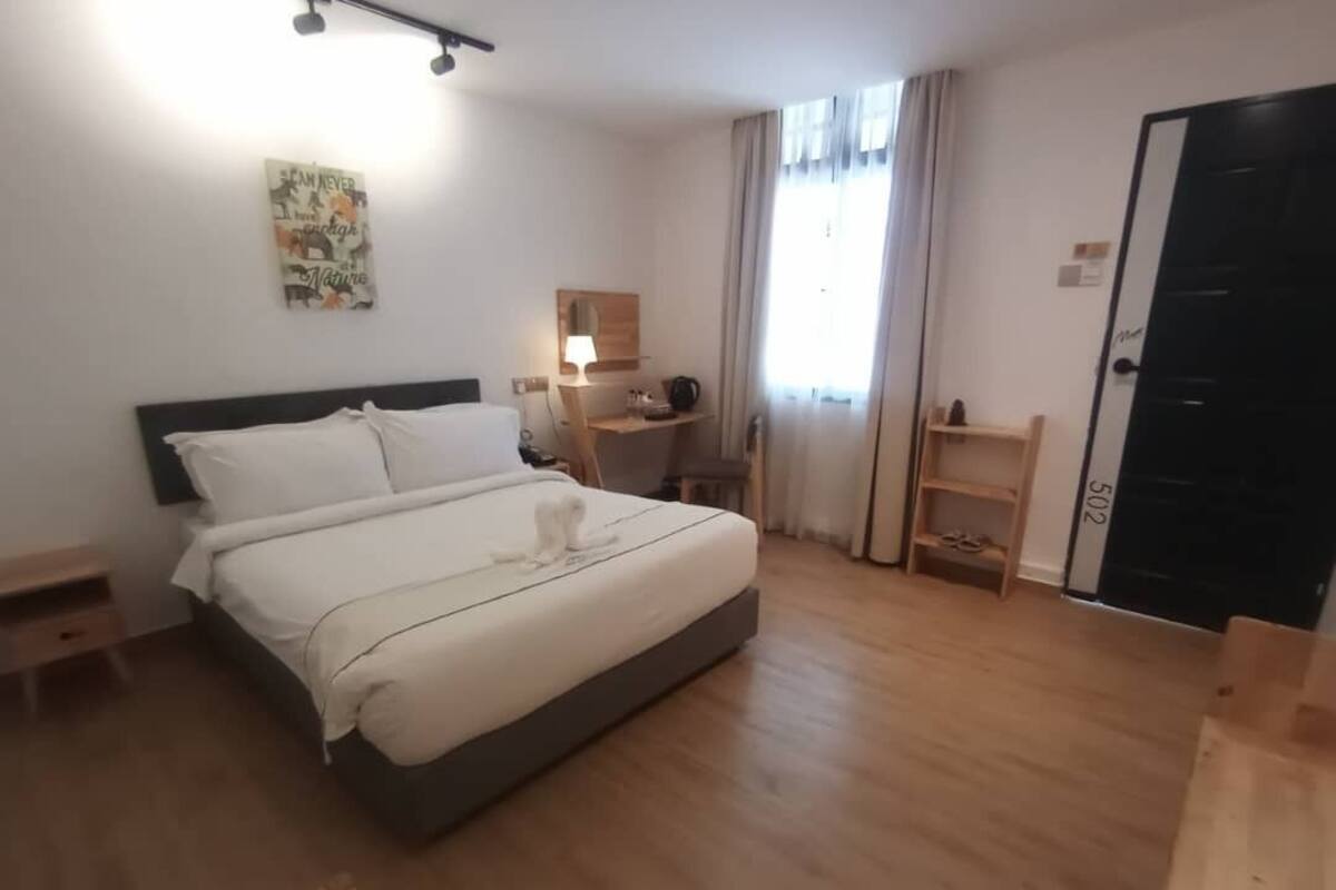Ein Hotelzimmer mit Bett, Schreibtisch, Stuhl, Lampe, Ablagefläche und Tür.