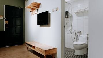 A minimalist bathroom with a wooden bench, a mounted television, and a shower area.