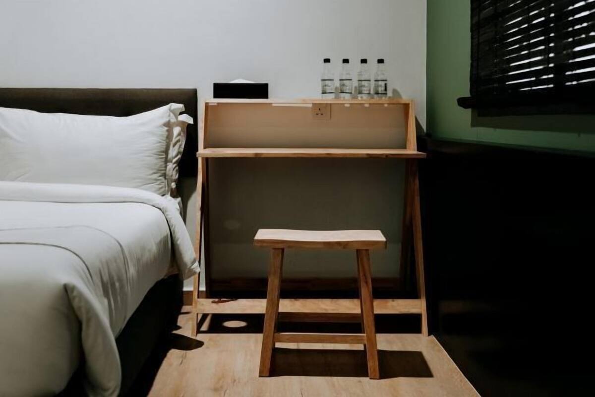 A bedroom with a bed, a wooden nightstand, and a small table.