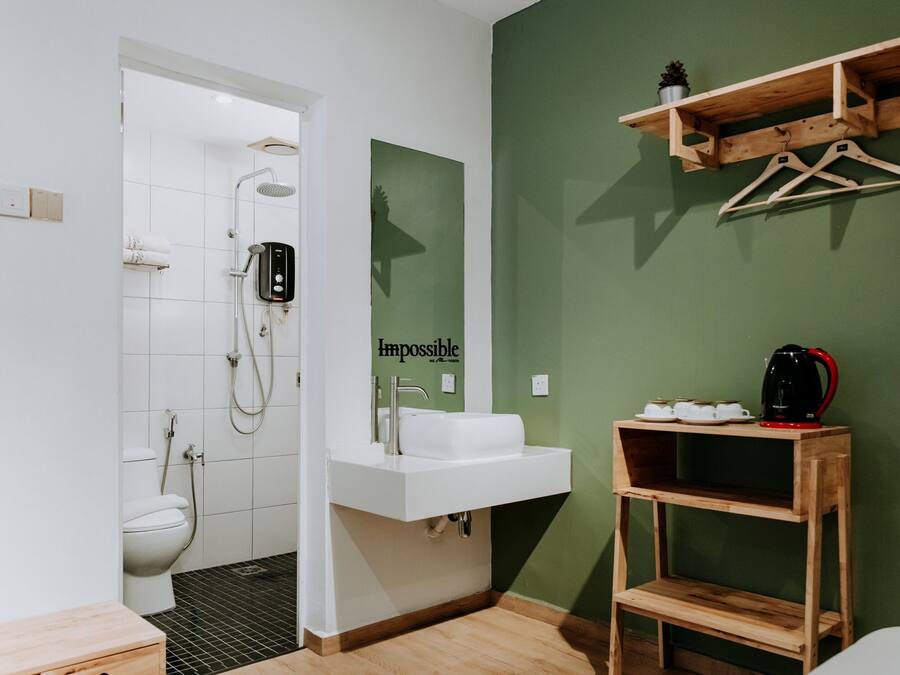 A bathroom with a shower, toilet, sink, and a shelf with a kettle and cups.