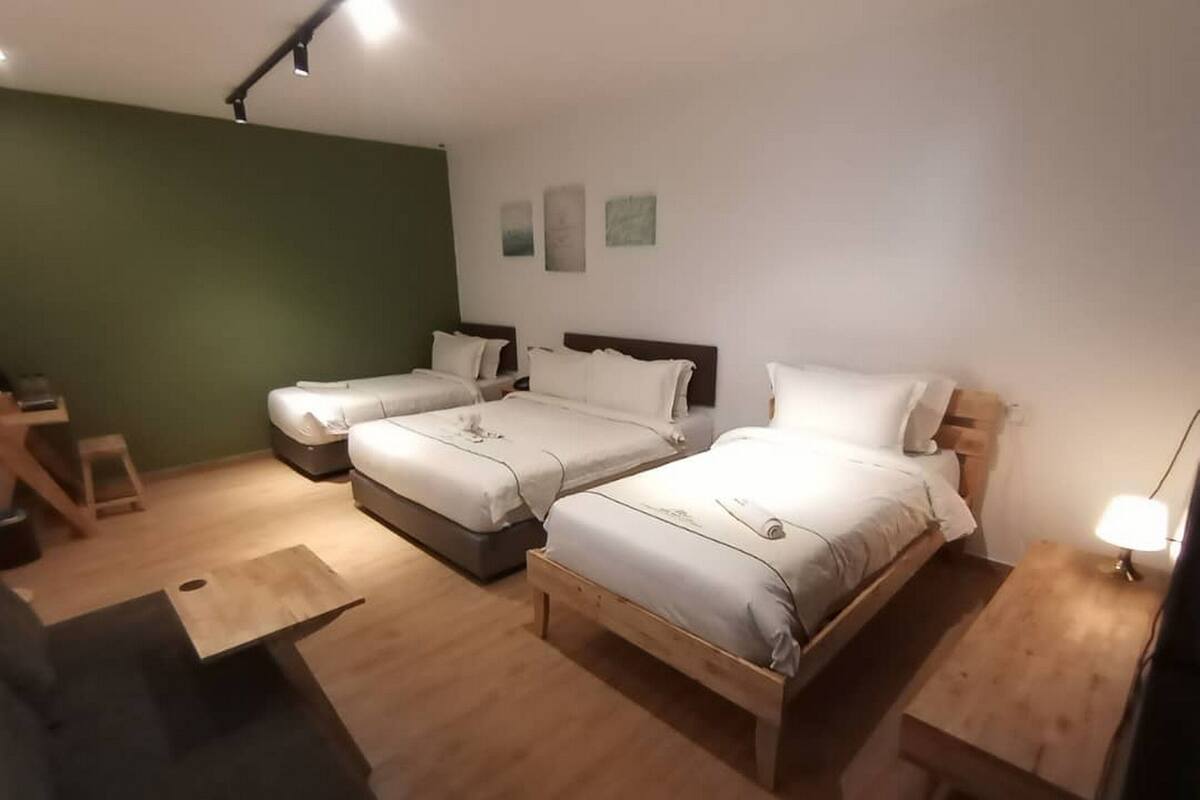 Ein Hotelzimmer mit drei Betten, einem Schreibtisch und einem Stuhl.
