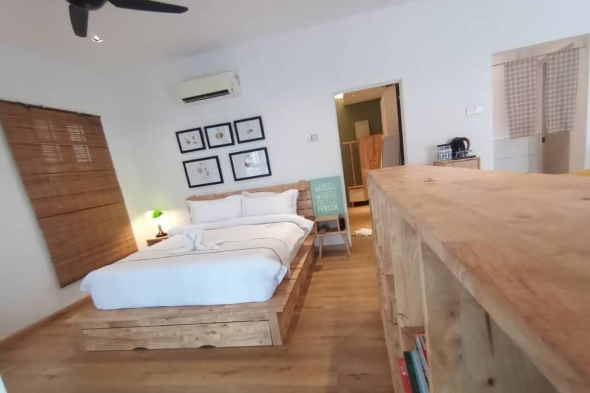 A bedroom with a wooden bed frame, a ceiling fan, and framed pictures on the wall.