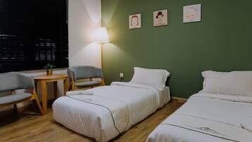 Habitación de hotel con dos camas, una mesita, dos sillas y una lámpara.