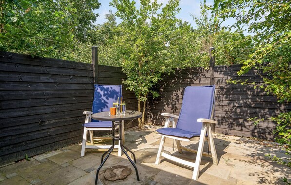 Relax in a serene outdoor space with two comfortable chairs and a small table for casual dining or conversation.
