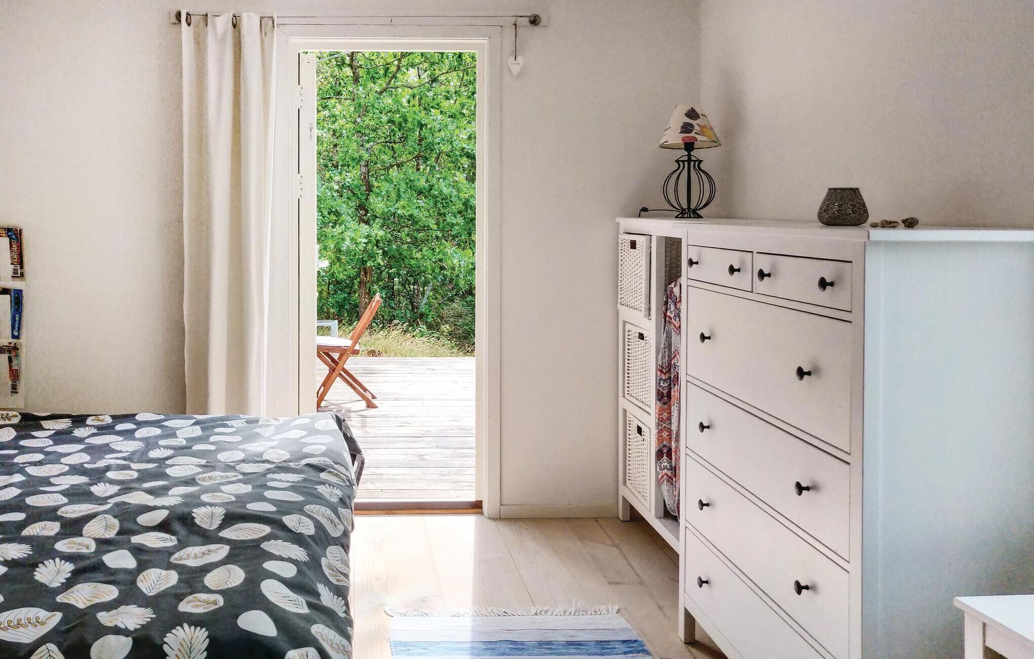 Ein Schlafzimmer mit Bett, Kommode und Blick ins Grüne.