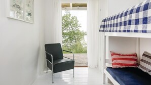 Une chambre avec un lit superposé, une chaise et une vue sur les arbres par la fenêtre.