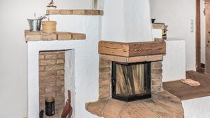 A fireplace with a rustic design, a brick wall, and a white ceiling.