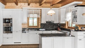 A modern kitchen with white cabinetry, a granite countertop, and a wooden ceiling.