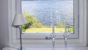 Une fenêtre donnant sur un lac, une lampe et deux chandeliers.