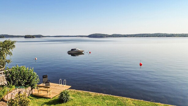 Un lac paisible avec un quai, un bateau et des bouées.