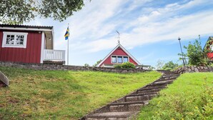 Un bâtiment rouge avec un balcon blanc, un drapeau et un escalier en pierre menant à l’étage supérieur.