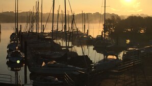 Ein Yachthafen mit mehreren angedockten Booten, klarem Himmel und Sonnenuntergang oder -aufgang.