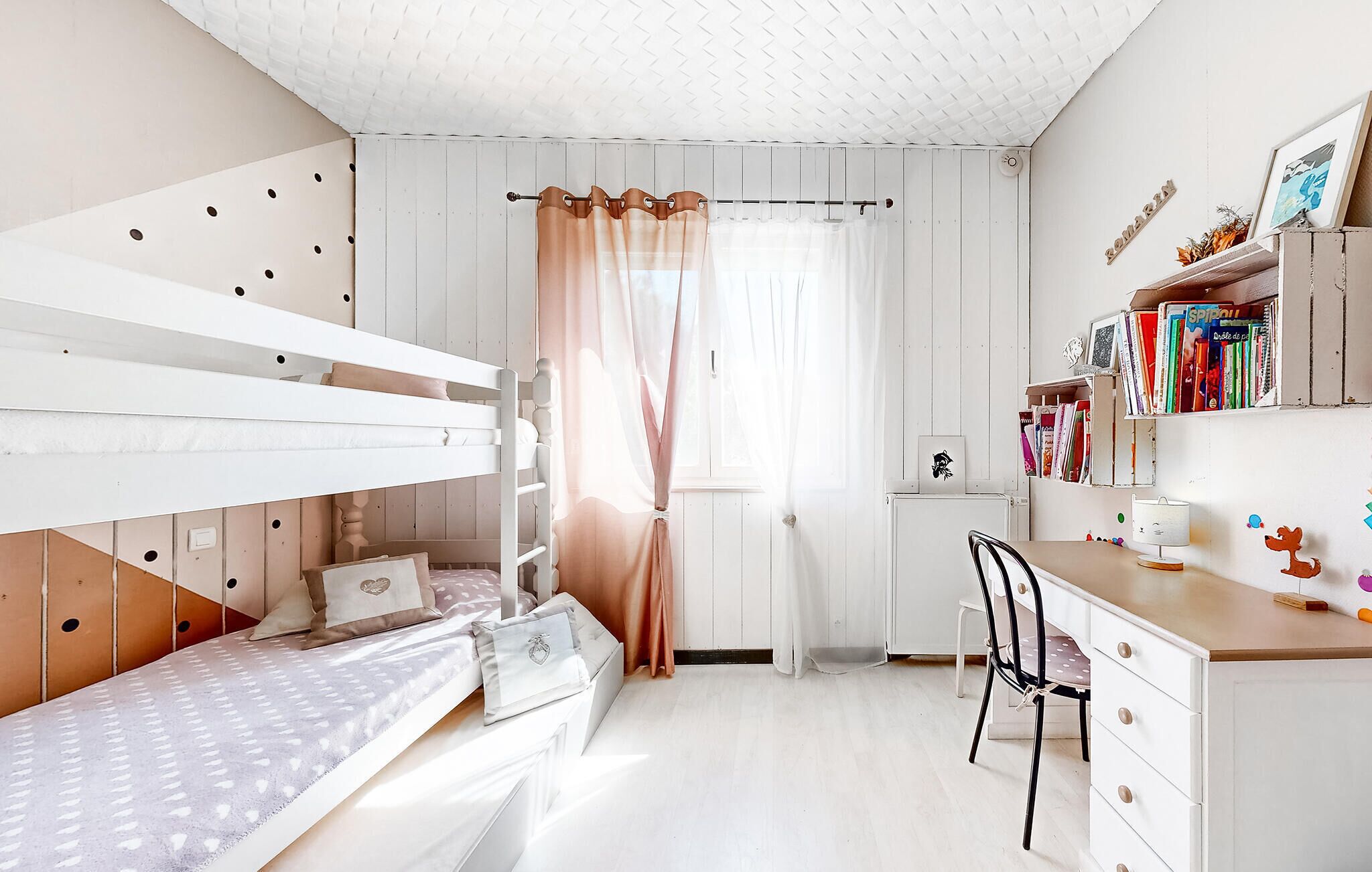 A child's bedroom with bunk beds, a desk, and a bookshelf.