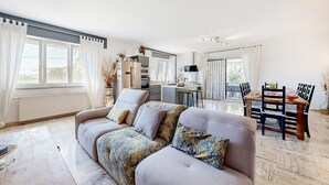 A modern living room with a sofa, a dining table with chairs, and a kitchen area visible through an open door. - Beautiful home in Lamotte Du Rhone (Lamotte Du Rhone)