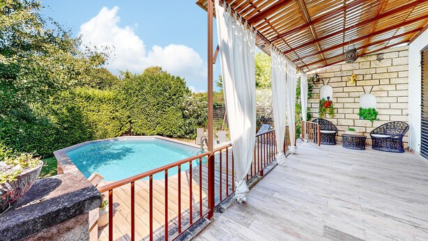 A pool area with a wooden deck, a pergola with a bamboo roof, and a brick wall with potted plants. - Beautiful home in Lamotte Du Rhone (Lamotte Du Rhone)