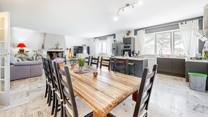 A modern kitchen with a central island, a dining area with a wooden table and chairs, and a living room with a sofa and a fireplace. - Beautiful home in Lamotte Du Rhone (Lamotte Du Rhone)