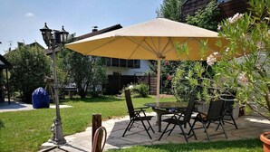 Un patio con tavolo e sedie, un ombrellone giallo e un lampione di strada.