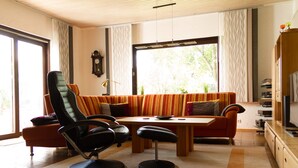Un soggiorno moderno con un divano, una poltrona nera, un tavolino da caffè e una televisione.